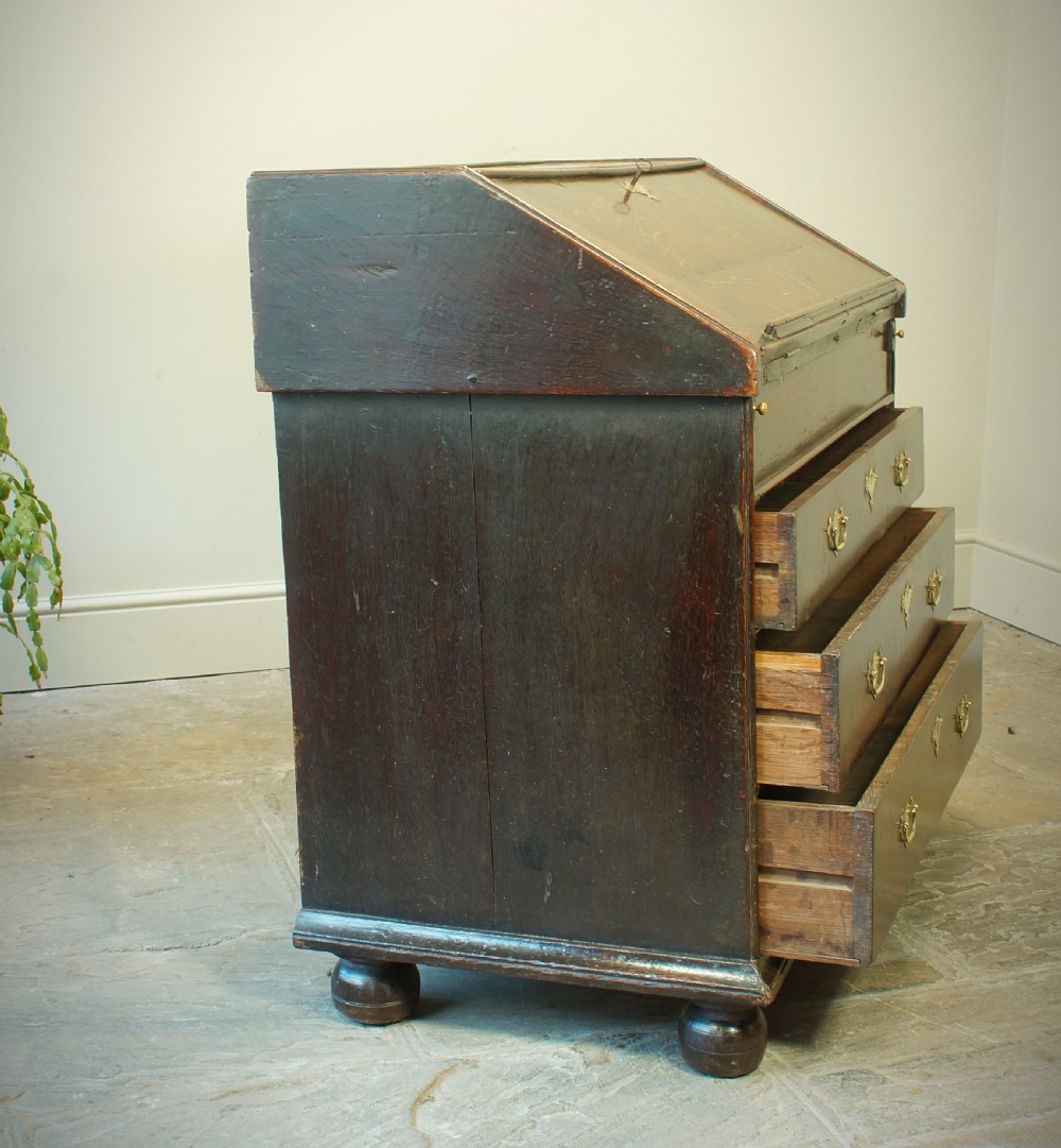 A William and Mary dark oak slant-front bureau featuring geometric parquetry on the lid, three long drawers with brass drop handles, and bun feet. View XI
