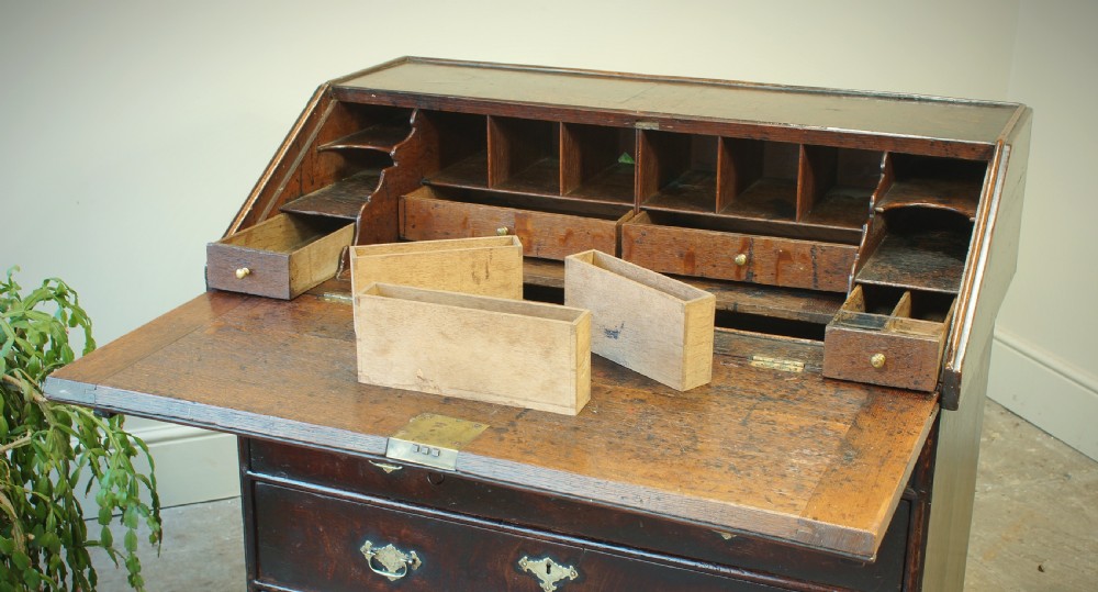 A William and Mary dark oak slant-front bureau featuring geometric parquetry on the lid, three long drawers with brass drop handles, and bun feet. View XIV
