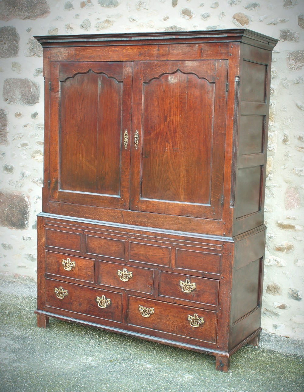 A Georgian oak linen press featuring two arched upper panel doors over a lower chest section with decorative brass hardware. View II
