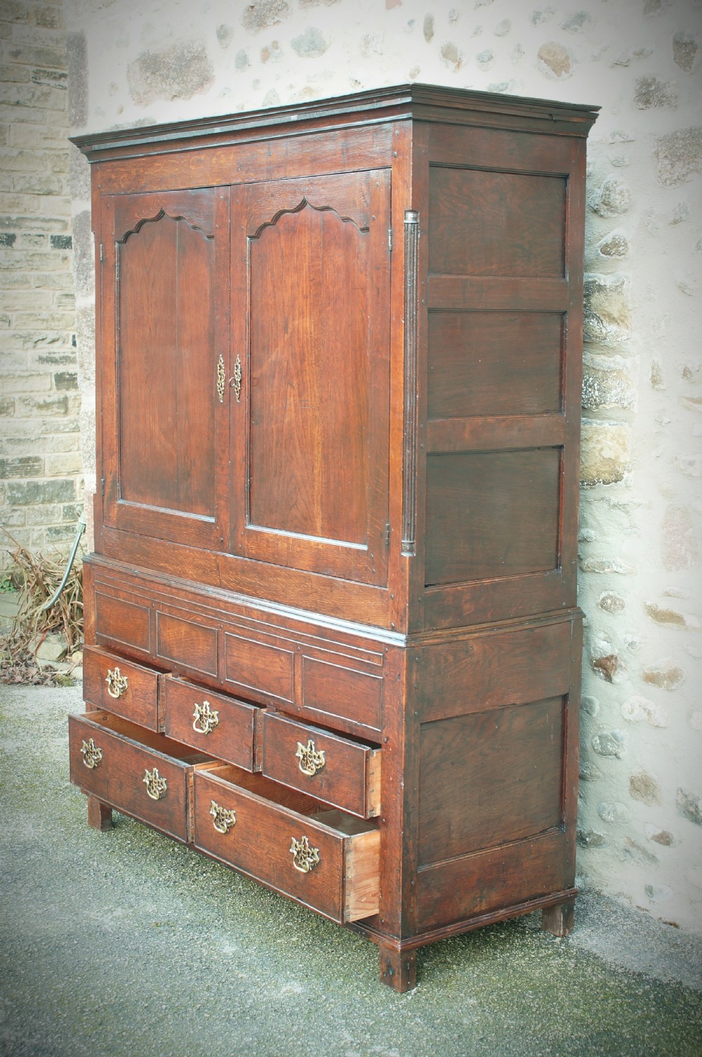 A Georgian oak linen press featuring two arched upper panel doors over a lower chest section with decorative brass hardware. View V