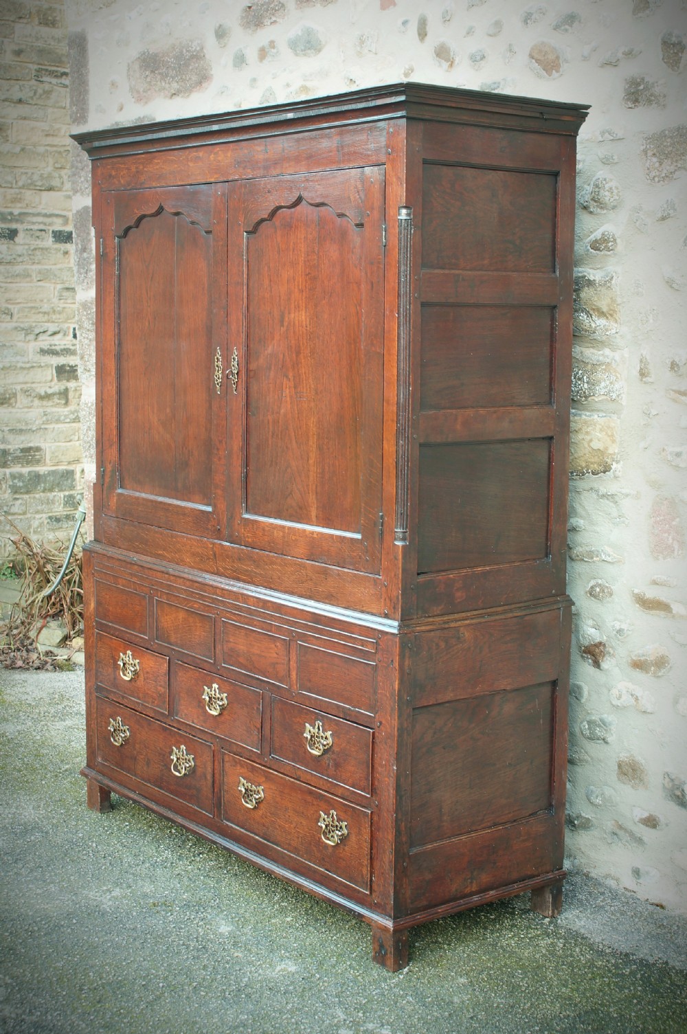 A Georgian oak linen press featuring two arched upper panel doors over a lower chest section with decorative brass hardware. View VI