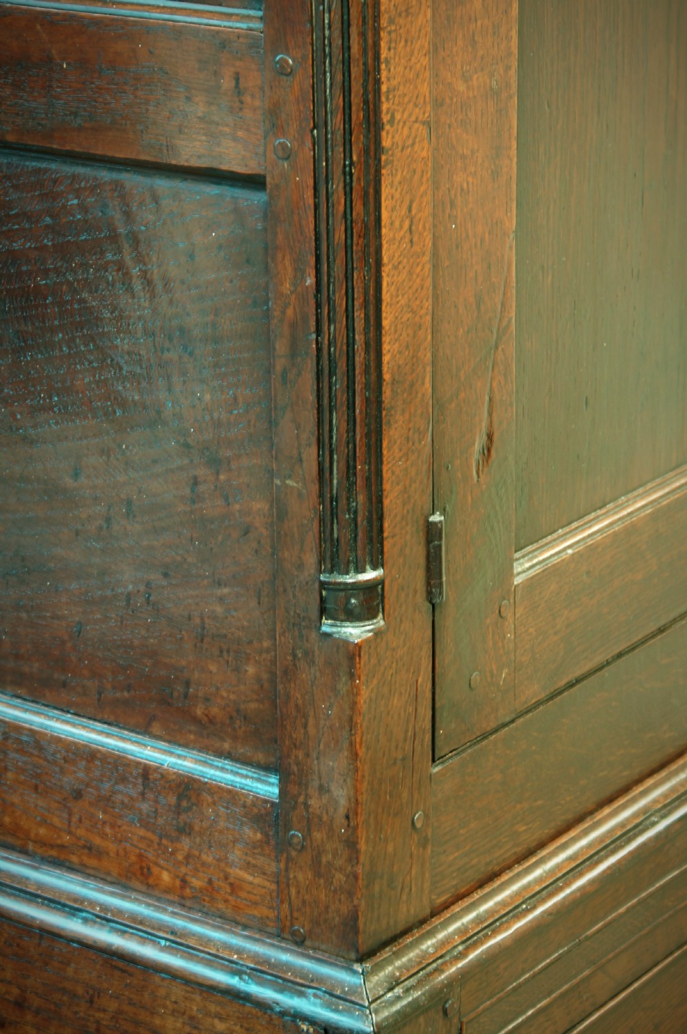 A Georgian oak linen press featuring two arched upper panel doors over a lower chest section with decorative brass hardware. View VII