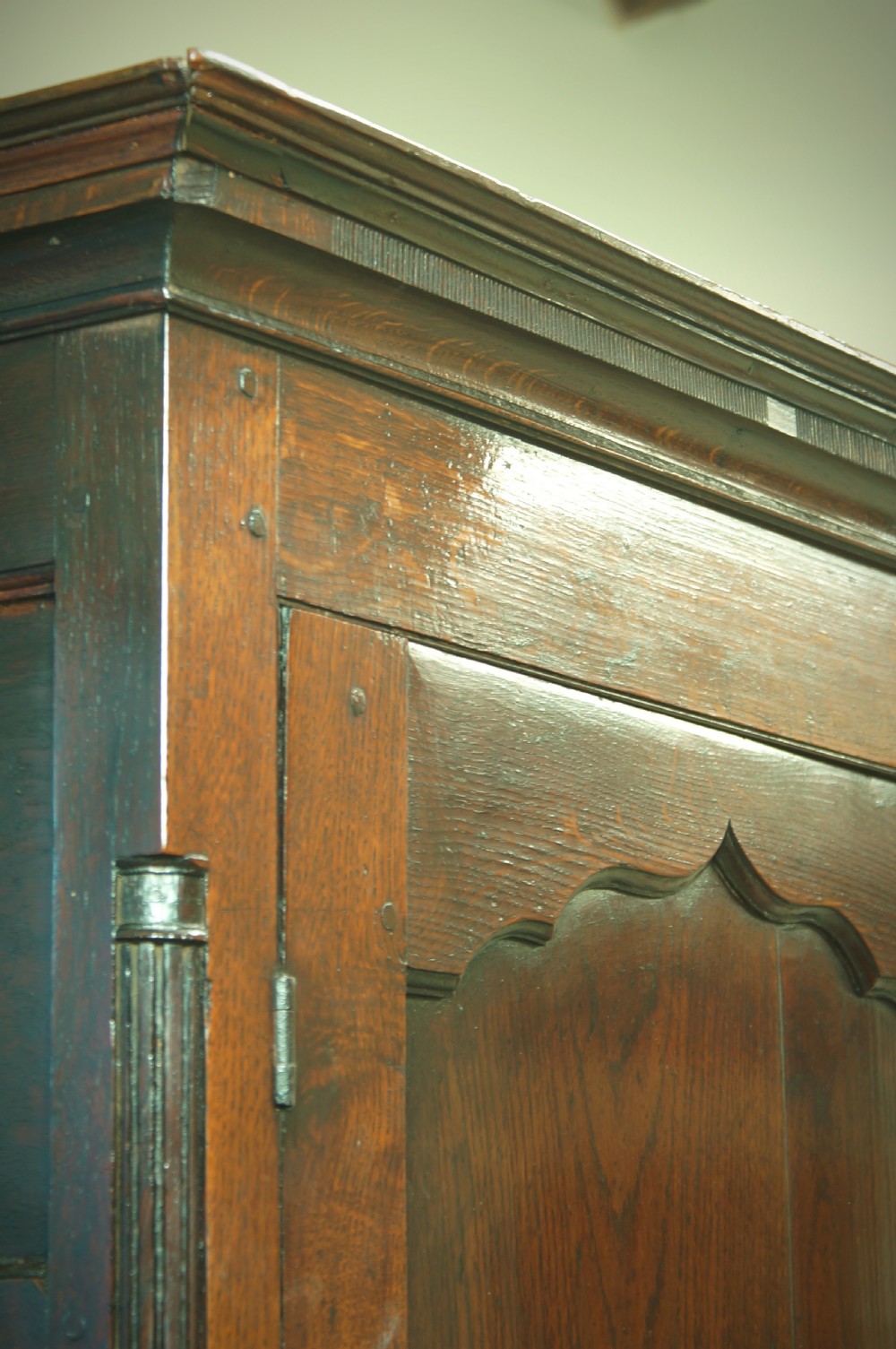 A Georgian oak linen press featuring two arched upper panel doors over a lower chest section with decorative brass hardware. View X