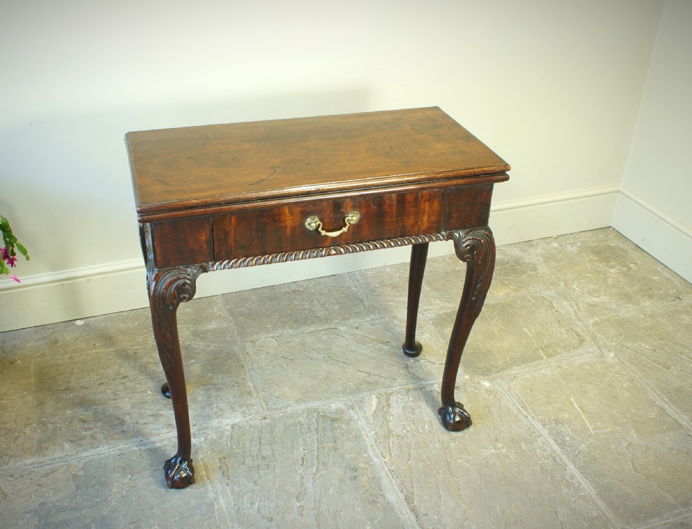 A George II mahogany fold-over card table featuring carved cabriole legs with ball-and-claw feet and a central drawer. View X