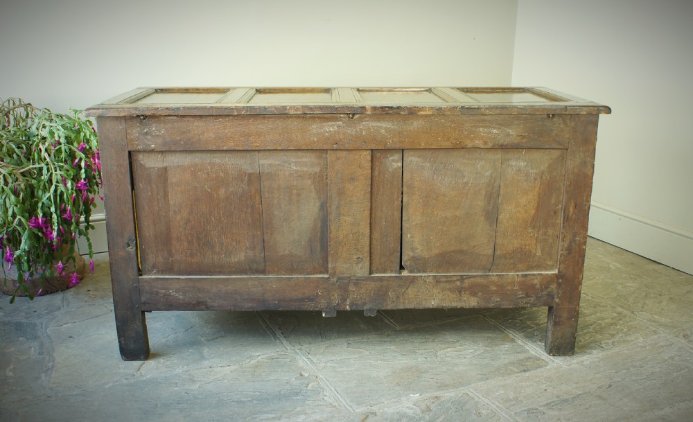 A 17th century dark oak mule chest featuring carved scrollwork front panels, two lower drawers with brass handles, and a panelled top lid. View XI