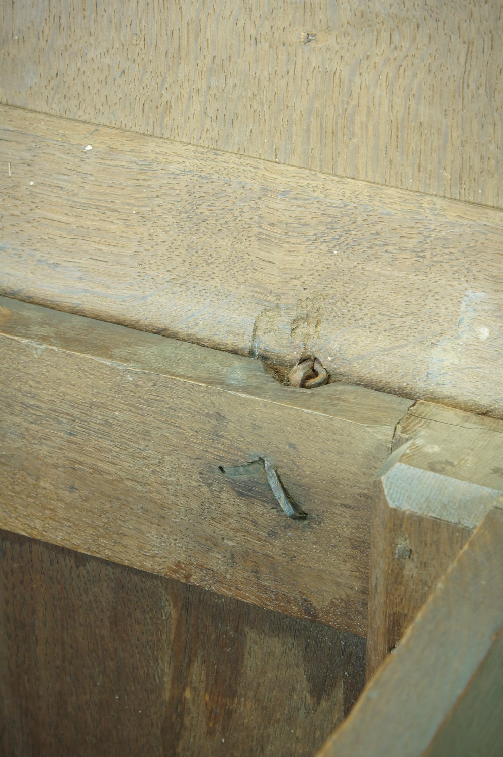 A 17th century dark oak mule chest featuring carved scrollwork front panels, two lower drawers with brass handles, and a panelled top lid. View XII