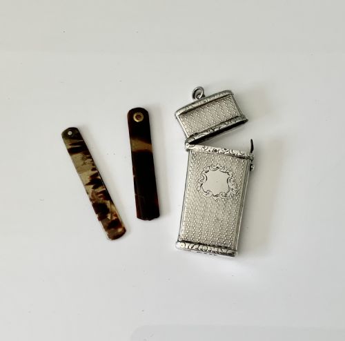 fig 1. An open Victorian engine-turned sterling silver medical etui featuring a blank central cartouche, suspension loop, and fitted interior containing folding lancets.