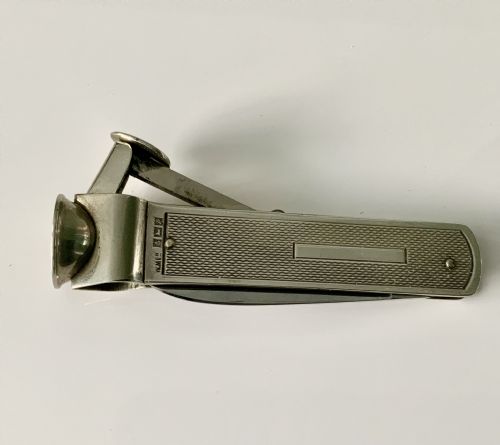 fig 1. A hallmarked sterling silver pocket knife featuring an engine-turned textured body, a single steel blade, and an integrated cigar cutter at the end.