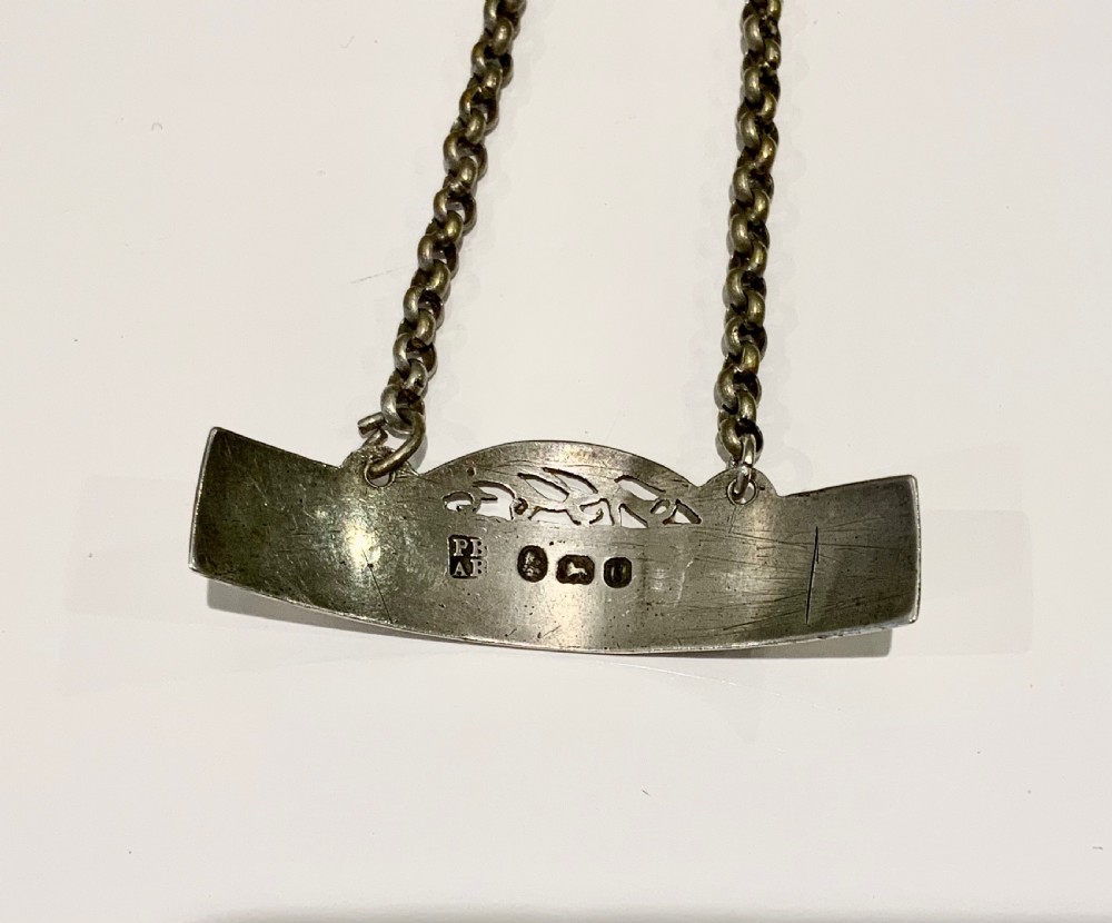 An antique Georgian sterling silver decanter label inscribed with SHERRY, featuring an engraved border, pierced crest, and attached chain. View III