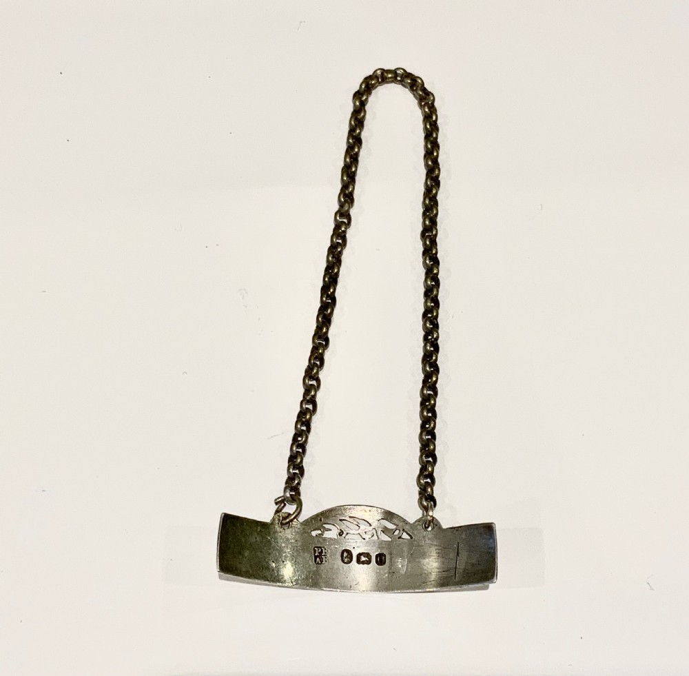 An antique Georgian sterling silver decanter label inscribed with SHERRY, featuring an engraved border, pierced crest, and attached chain. View IV