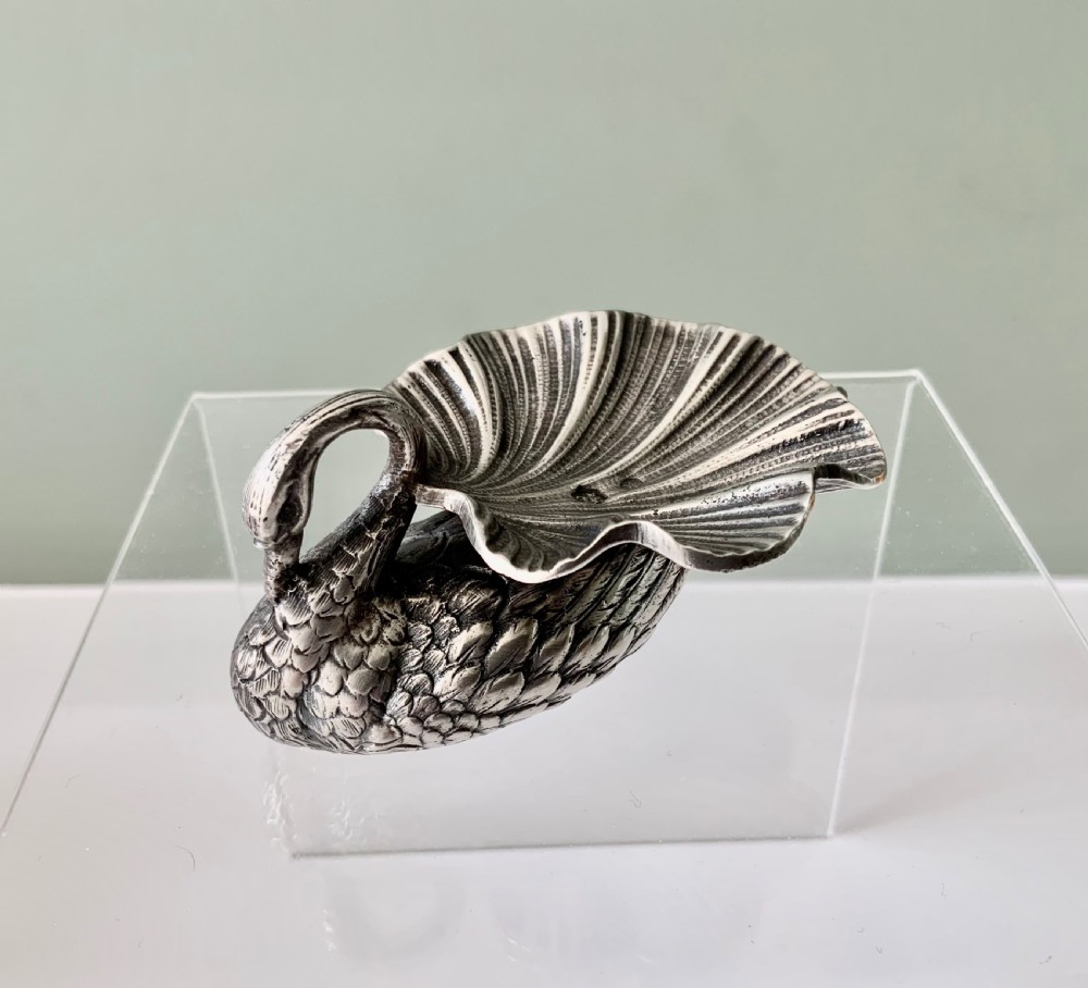 A silver salt cellar fashioned in the shape of a swan with detailed feather texture and a ribbed shell-shaped dish on its back.