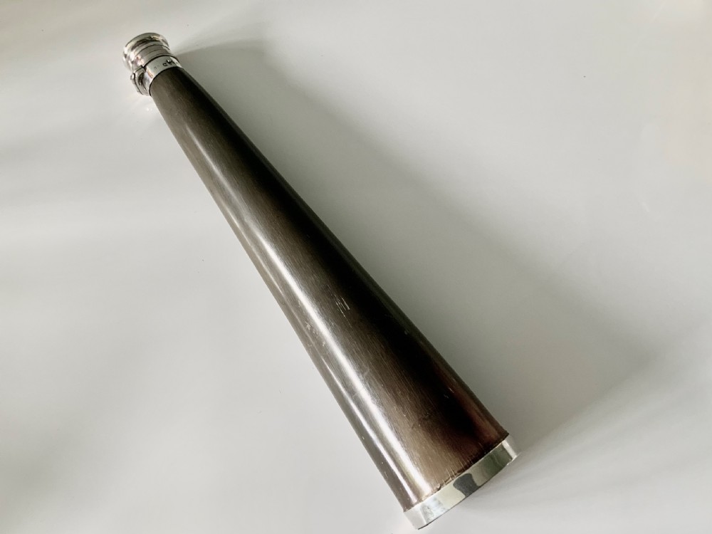 A conical antique spirit flask constructed from dark natural horn with polished silver mounts on the cap and base.