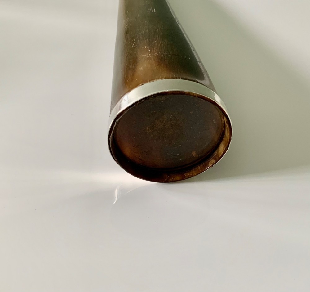 A conical antique spirit flask constructed from dark natural horn with polished silver mounts on the cap and base. View II