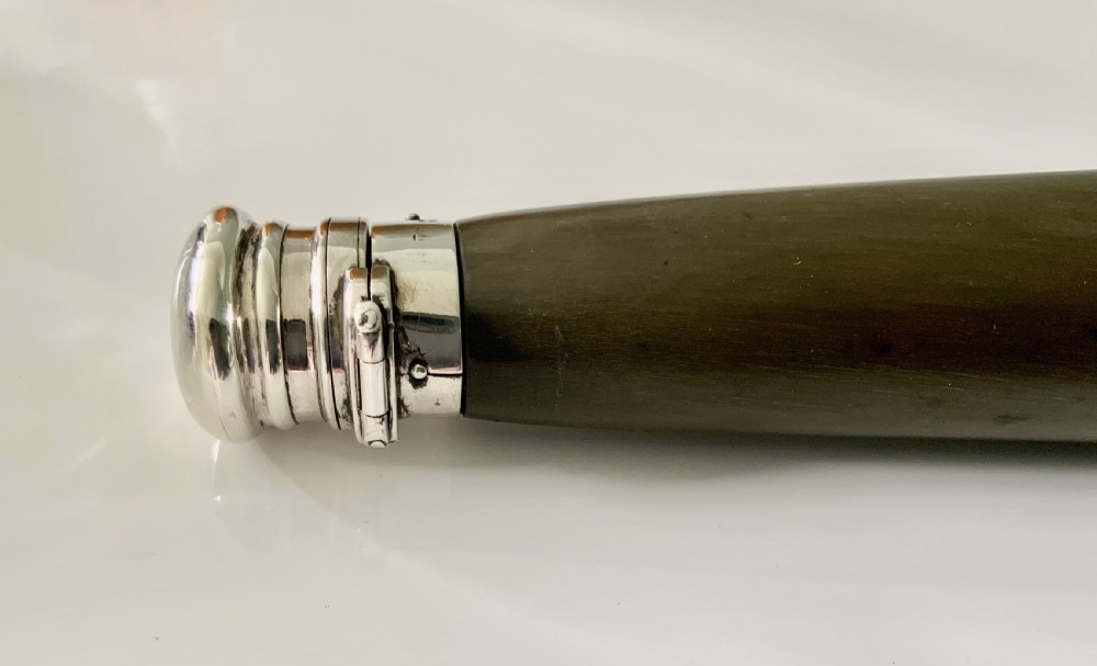A conical antique spirit flask constructed from dark natural horn with polished silver mounts on the cap and base. View VII