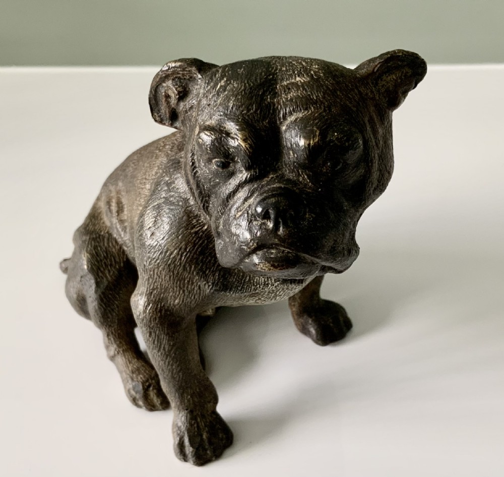 A dark cold-painted bronze sculpture of a bulldog seated on its hind legs.