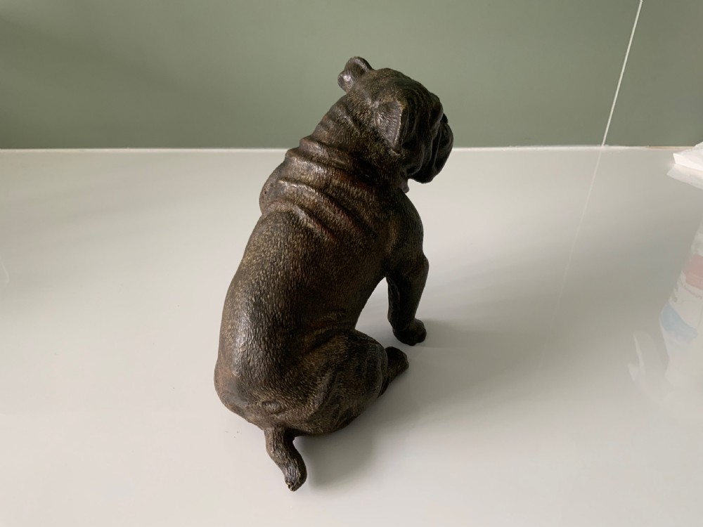 A dark cold-painted bronze sculpture of a bulldog seated on its hind legs. View IV