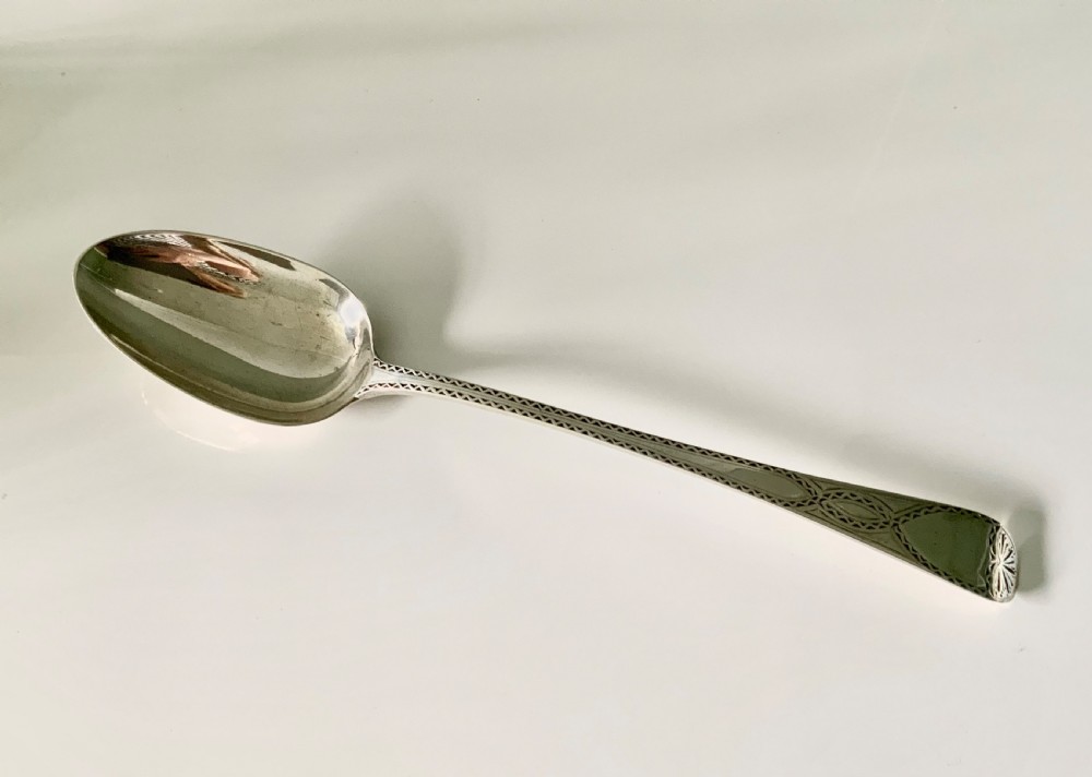 A Victorian sterling silver gravy spoon featuring an elongated oval bowl and a tapered handle decorated with geometric borders.