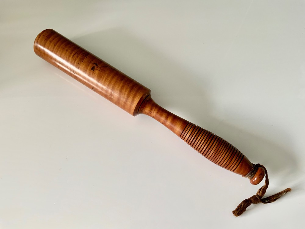 A turned 19th-century satin birch veterinary fleam mallet featuring a cylindrical striking head, a ribbed handle grip, and a tied leather strap. View II