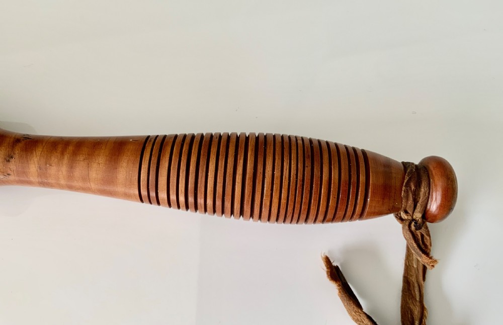 A turned 19th-century satin birch veterinary fleam mallet featuring a cylindrical striking head, a ribbed handle grip, and a tied leather strap. View IV