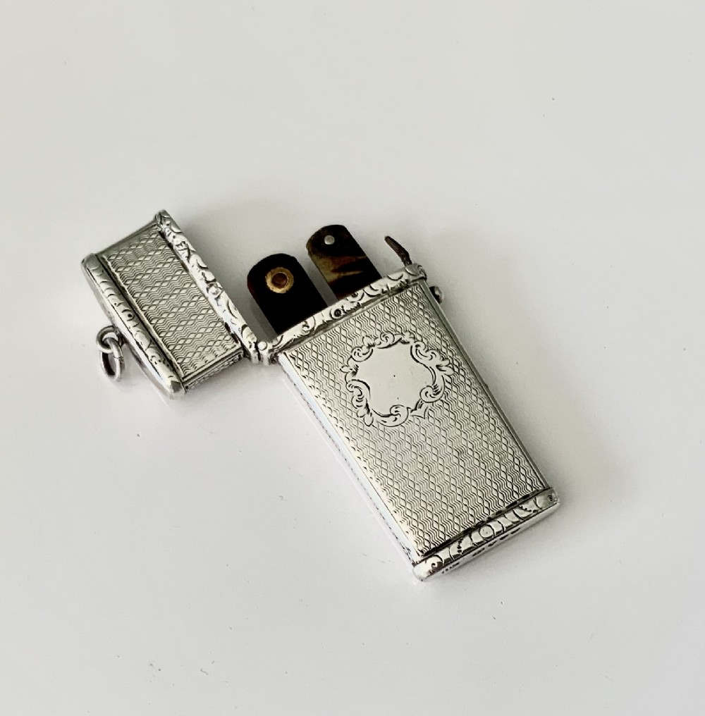 An open Victorian engine-turned sterling silver medical etui featuring a blank central cartouche, suspension loop, and fitted interior containing folding lancets.