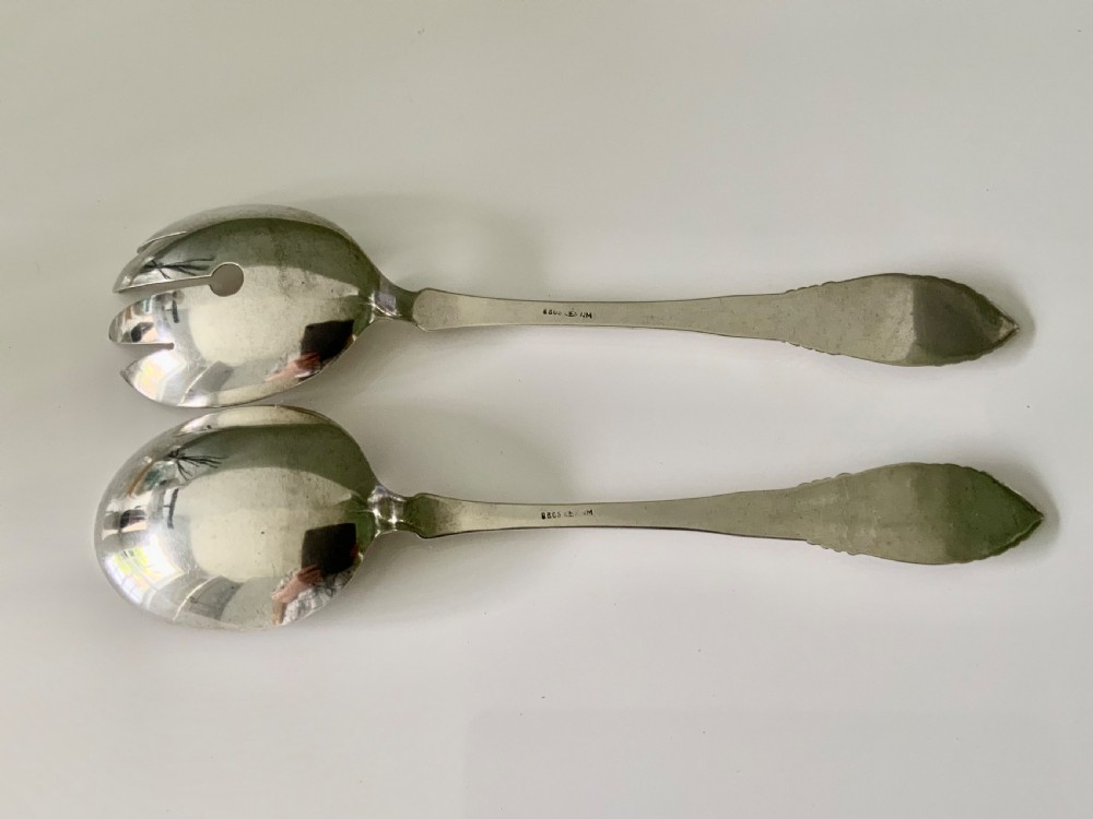 A pair of silver salad servers consisting of a spoon and a three-pronged fork with relief motifs on the handles. View II