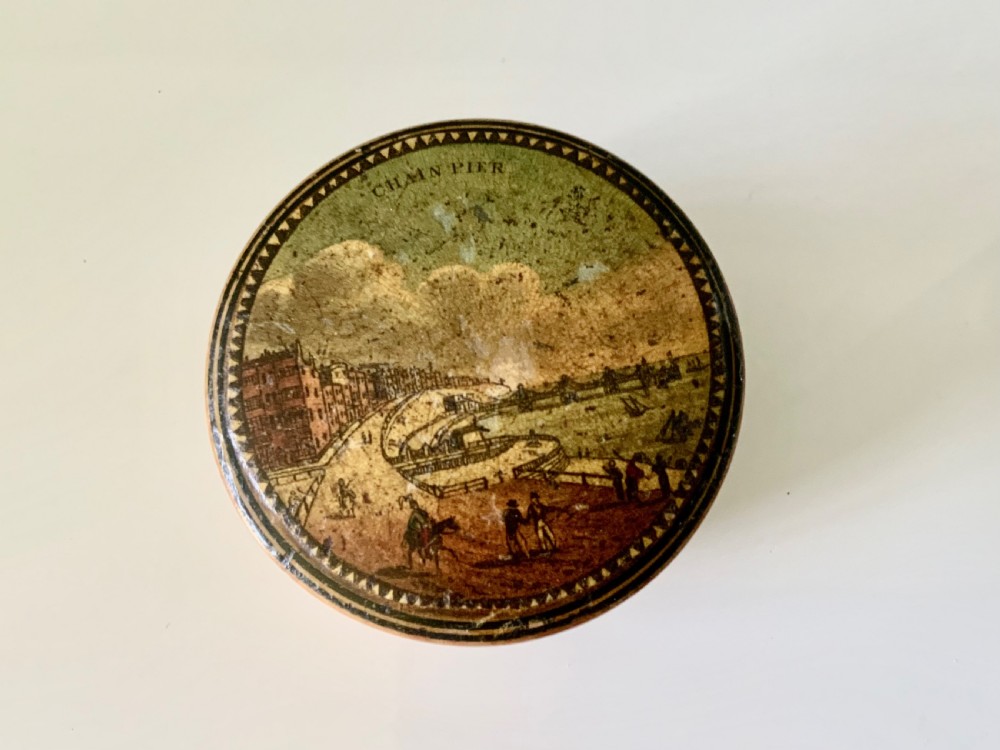 A circular 19th-century turned wooden box featuring a lid with a topographical print of the Brighton Chain Pier framed by a sawtooth border.