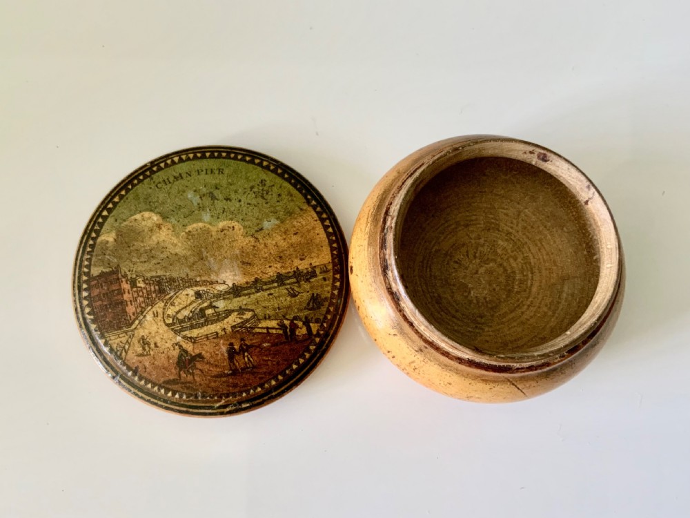 A circular 19th-century turned wooden box featuring a lid with a topographical print of the Brighton Chain Pier framed by a sawtooth border. View II