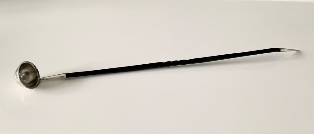 An antique Scottish provincial silver condiment ladle featuring a circular silver bowl, a long twisted black horn stem, and a silver pointed finial.