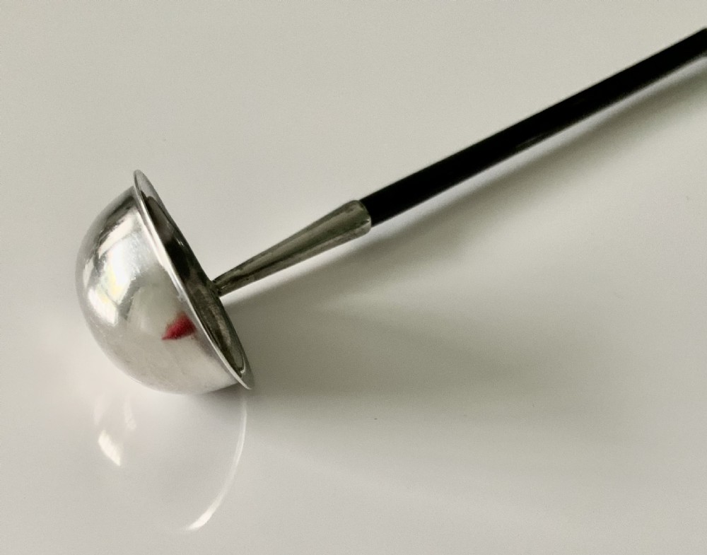 An antique Scottish provincial silver condiment ladle featuring a circular silver bowl, a long twisted black horn stem, and a silver pointed finial. View III