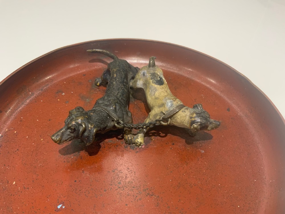 An antique round bronze tray featuring two cold painted dog figures affixed to the interior surface. View II