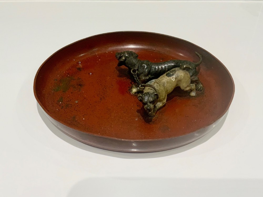 An antique round bronze tray featuring two cold painted dog figures affixed to the interior surface. View III
