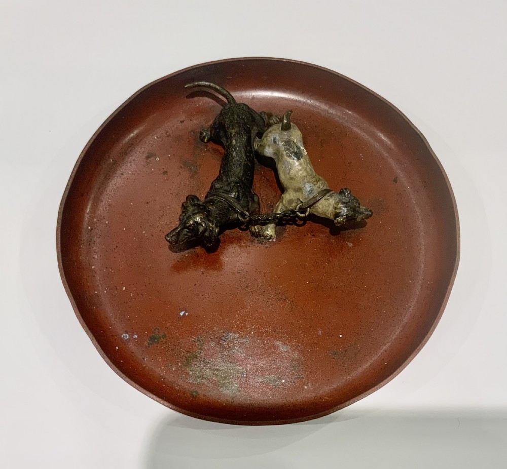 An antique round bronze tray featuring two cold painted dog figures affixed to the interior surface. View IV