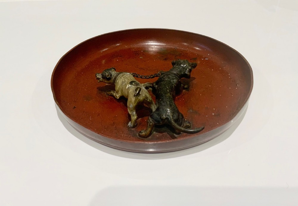 An antique round bronze tray featuring two cold painted dog figures affixed to the interior surface. View V