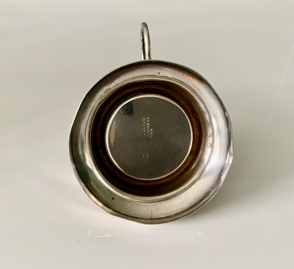 A Victorian silver night light holder featuring a rounded base holding a small wax candle beneath a scalloped shell-shaped reflector shade. View VI