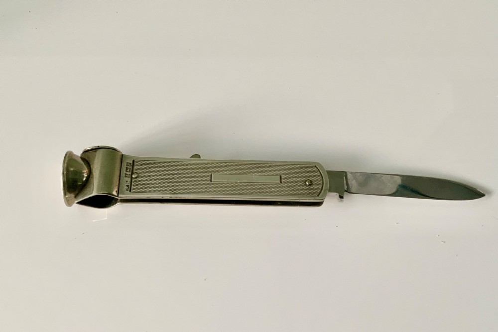 A hallmarked sterling silver pocket knife featuring an engine-turned textured body, a single steel blade, and an integrated cigar cutter at the end.