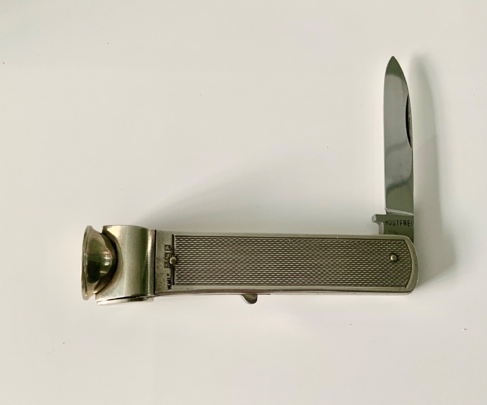 A hallmarked sterling silver pocket knife featuring an engine-turned textured body, a single steel blade, and an integrated cigar cutter at the end. View V