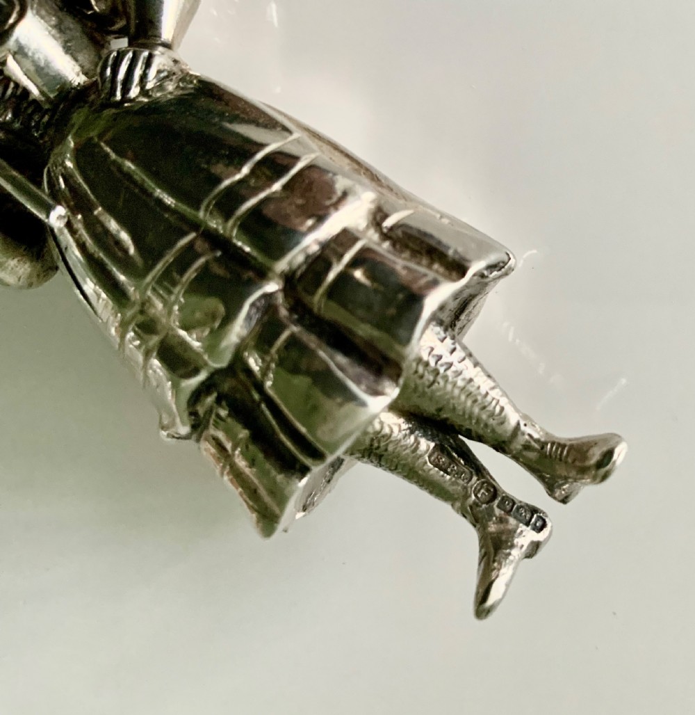 A cast silver perfume bottle sculpted in the form of a standing woman wearing a bonnet and dress while holding a staff. View V