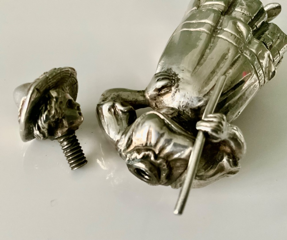 A cast silver perfume bottle sculpted in the form of a standing woman wearing a bonnet and dress while holding a staff. View VII