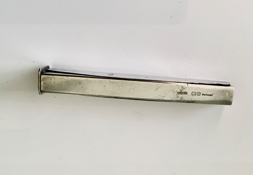 An antique sterling silver rectangular wax holder sheath with visible hallmarks containing a stick of red sealing wax. View III
