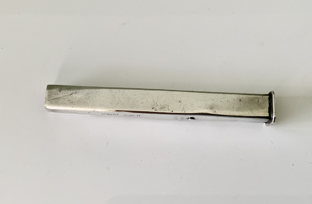 An antique sterling silver rectangular wax holder sheath with visible hallmarks containing a stick of red sealing wax. View V