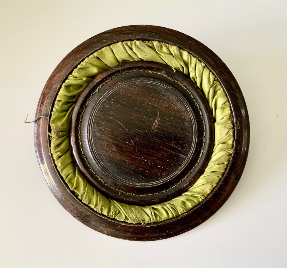 A circular Regency era wooden sewing basket featuring geometric Tunbridge Ware mosaic inlay along the rim, an optical cube parquetry base, green pleated silk interior lining, and an arched handle. View III