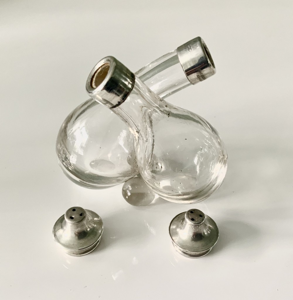 A clear glass double cruet bottle with hallmarked silver tops joined together in an intertwined design. View IV