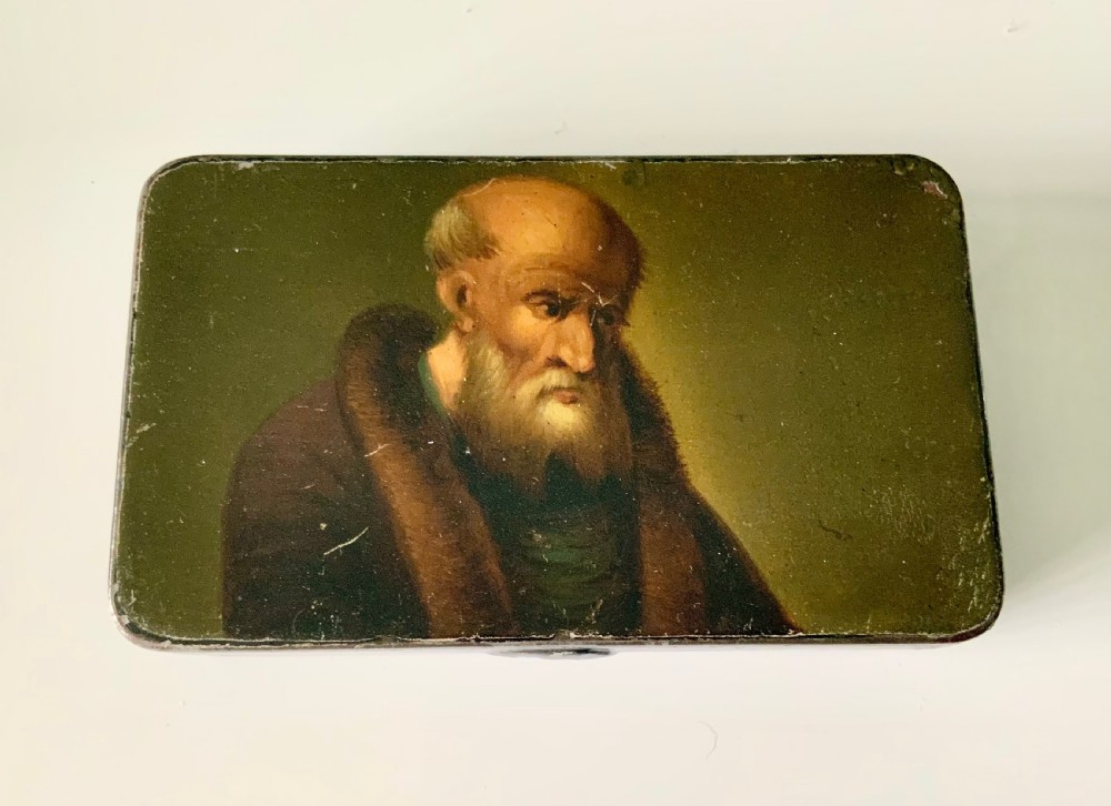 An early 19th-century rectangular painted tin snuff box featuring a hand-painted portrait of a bearded man on the olive green lid.