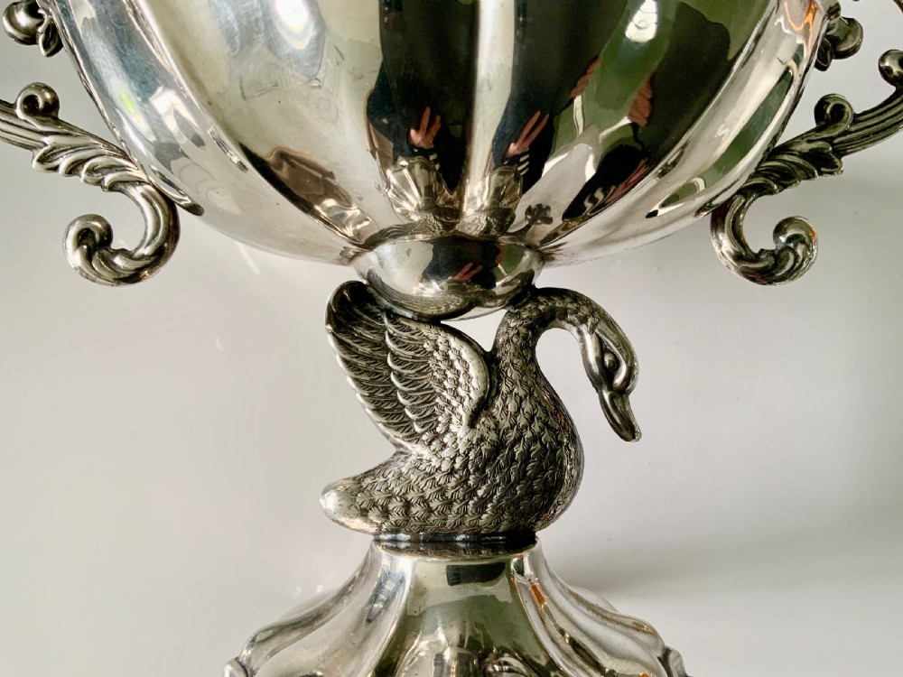 A polished silver dish featuring a lobed rim, two ornate scroll handles, and a central swan motif on a flared pedestal base. View VII