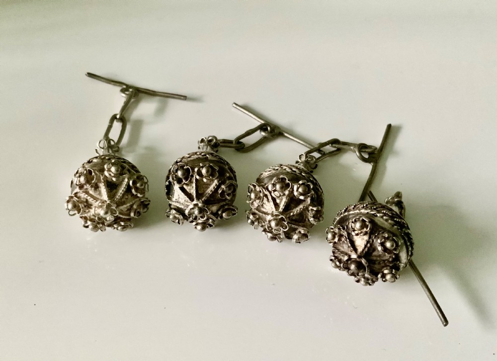 Four 19th-century Maltese silver filigree spherical buttons with attached chain links and toggle bars.