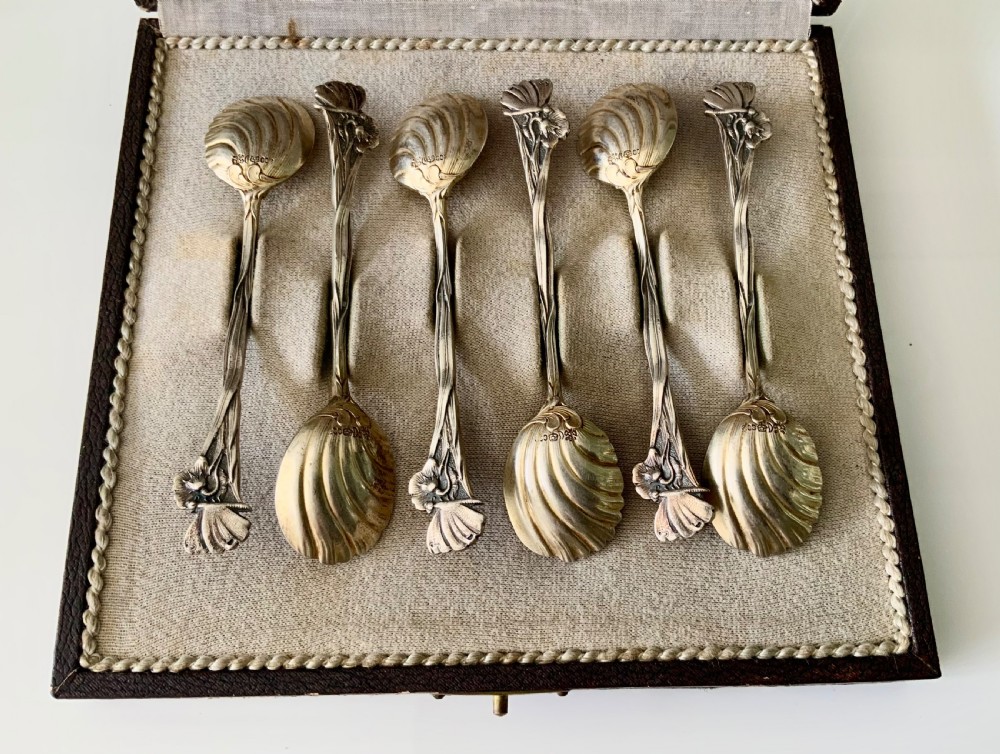 A set of six Art Nouveau silver teaspoons with shell bowls and floral stems, displayed inside an open fitted cloth-lined presentation box. View III