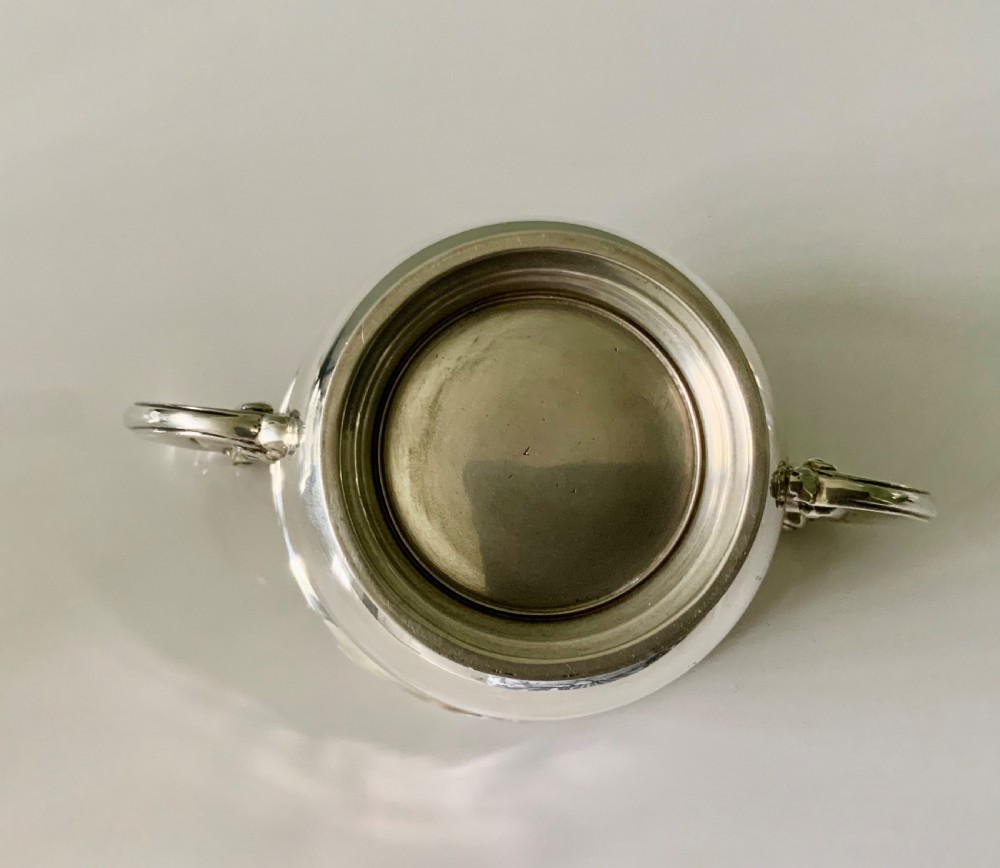 A polished silver loving cup featuring two prominent scroll handles and embossed leaf detailing around the body. View V