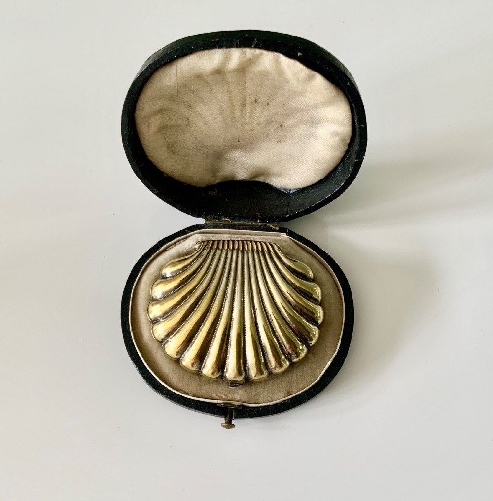 A 19th-century French silver gilt shell-shaped coin purse resting inside its open original fitted presentation box lined with cream silk.
