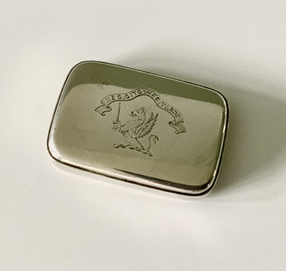 A rectangular Victorian sterling silver vesta case featuring an engraved crest of a winged griffin with a sword above a heraldic motto ribbon.