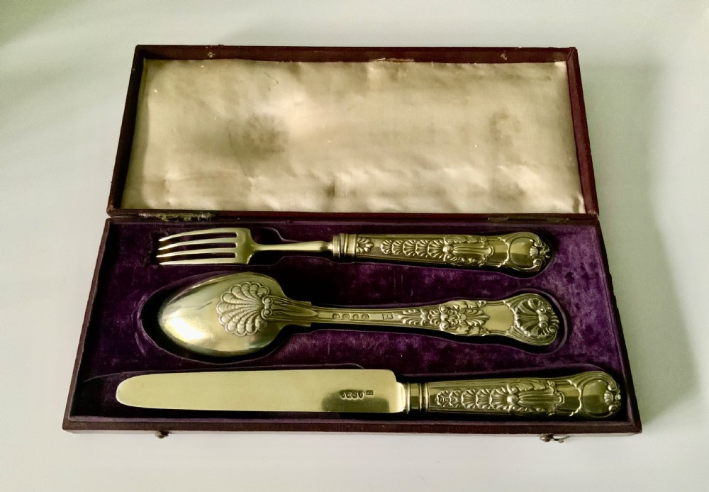 A three-piece Georgian silver cutlery set in the Coburg pattern, presented inside a velvet-lined display case.